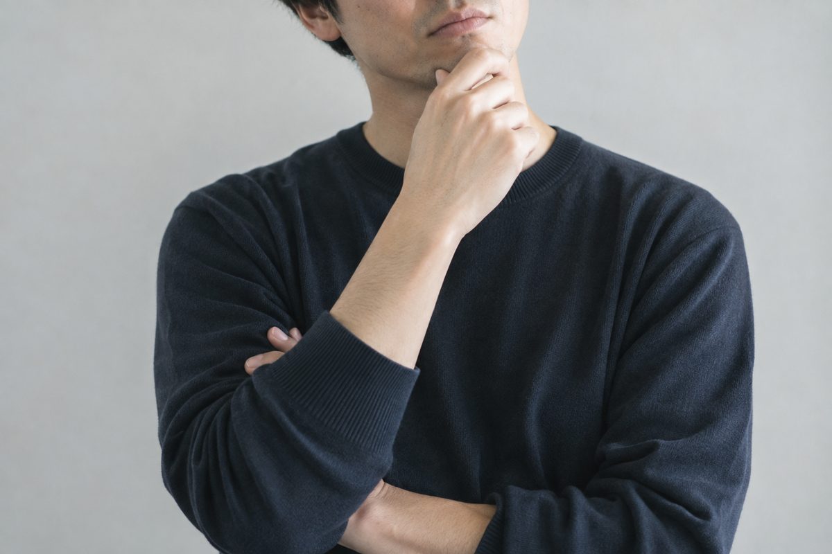 ソファで資料を確認しながら考え事をしている男性
